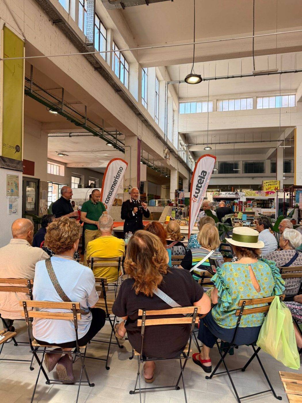Roma: il pubblico dell'incontro al mercato, con le vele di Consumerismo e +Tutela